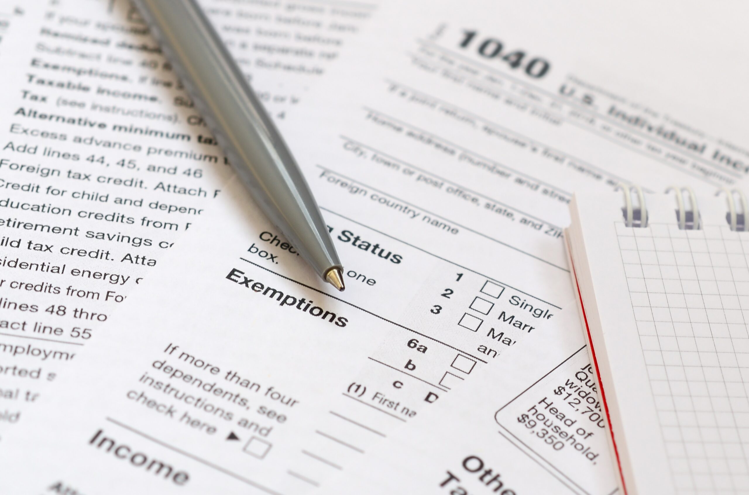 The pen and notebook is lies on the tax form 1040 U.S. Individua